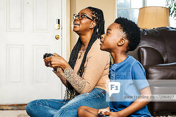 Mother and son playing video game in living room at home