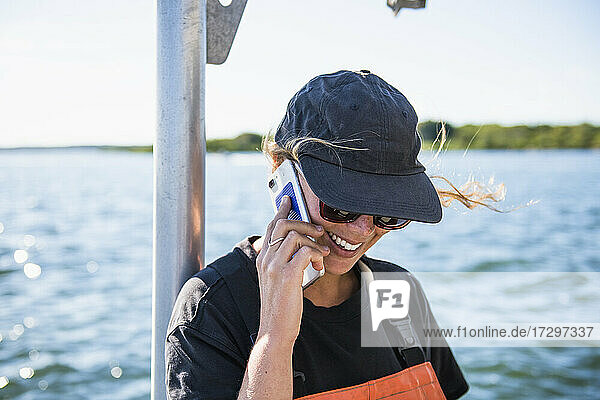 Frau am Telefon bei der Arbeit auf dem Wasser in einer Aquakultur-Austernzucht