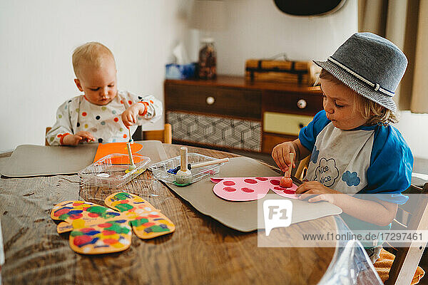 Kleine Kinder malen zu Hause Schmetterlinge und sind dabei kreativ und unordentlich