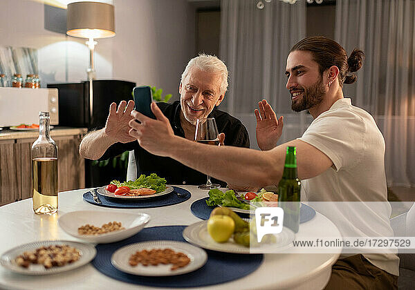 Junge und ältere Männer nutzen ein Smartphone für einen Videoanruf
