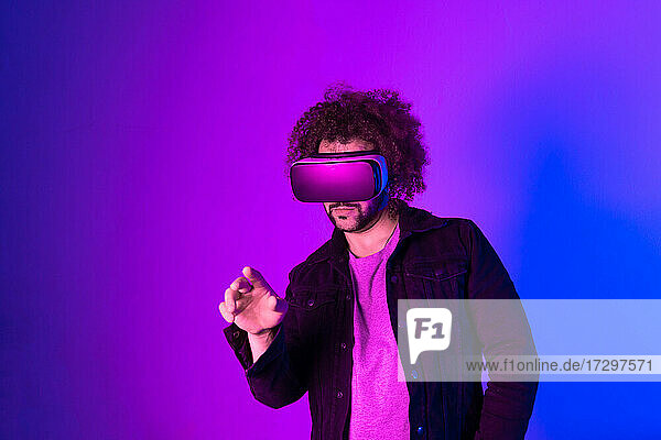 Hipster junger Mann mit Virtual-Reality-Headset über blau-lila