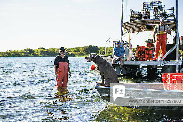 Besatzung und Hund bei der Arbeit auf dem Wasser in einer Aquakultur-Austernzucht