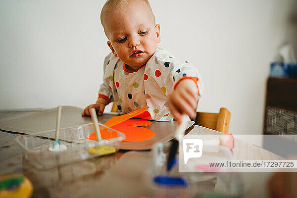 Adorable toddler painting at home doing crafts in pandemic lockdown