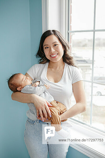 Chinesische asiatische Mutter hält neugeborenen Säugling Baby Sohn. Glückliche Familie.