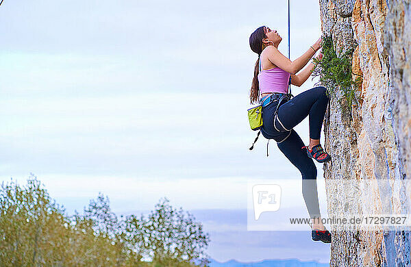 Profilfoto einer jungen Frau  die eine steile Felswand erklimmt