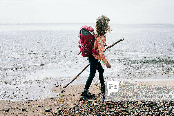 Mädchen  das an einem schönen Tag im Vereinigten Königreich mit einem Stock an der Juraküste spazieren geht