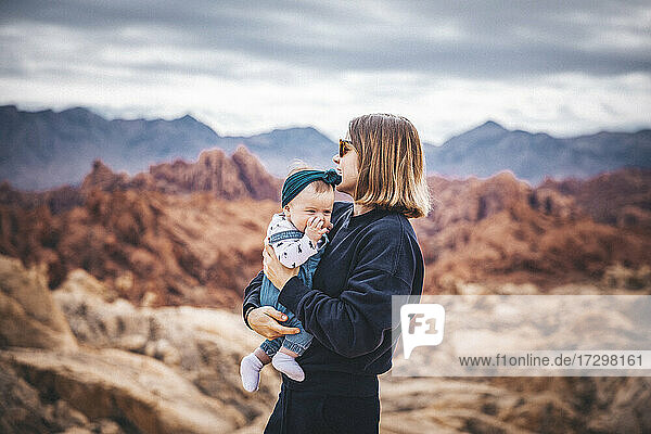 Eine junge Frau mit einem Baby steht in der Nähe von roten Felsen im Valley of Fire