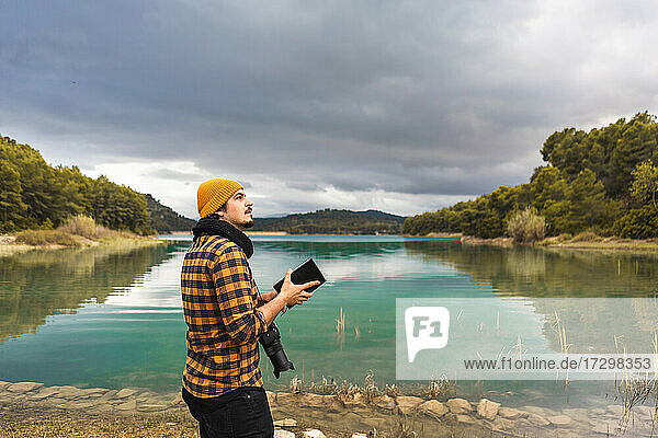 Tourist guide cheking guide book with hat and camera in the lake