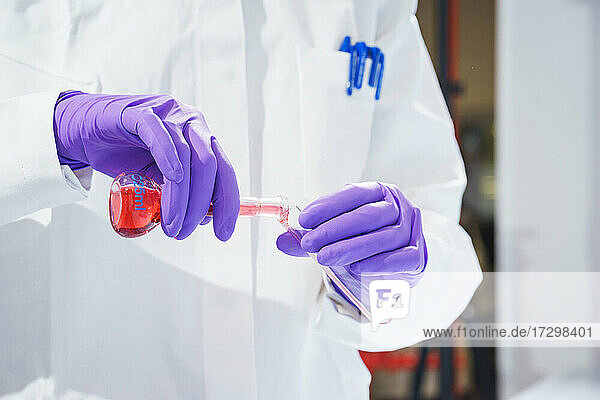 Forscher hält einen Kolben mit Chemikalien und Reagenzien in den Händen