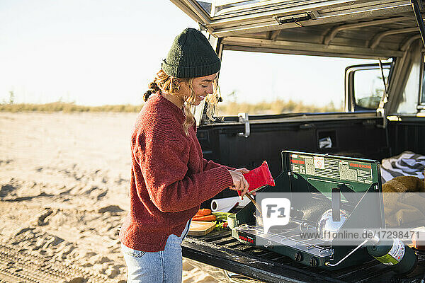 Junge Frau Heckklappe Kochen während Strand Auto Camping allein