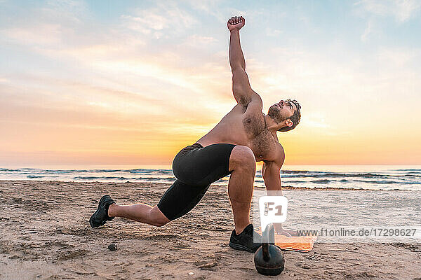 muscular man training on the beach at sunrise