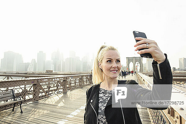 Glückliche Frau nimmt Selfie auf Fußgängerüberführung in Megapolis