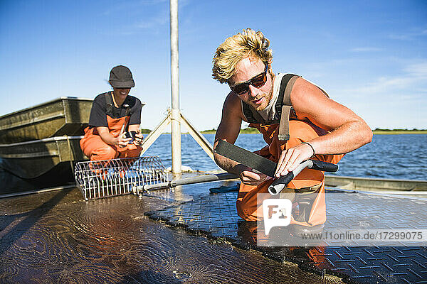 Junger Mann bei der Arbeit auf dem Wasser in der Aquakultur Austernzucht