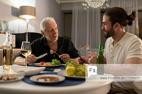 Elderly and young men chatting during dinner