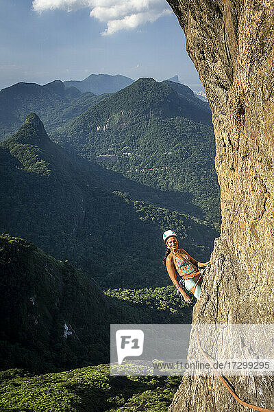 Schöner Blick auf Bergsteigerin auf steilem felsigem Regenwaldberg