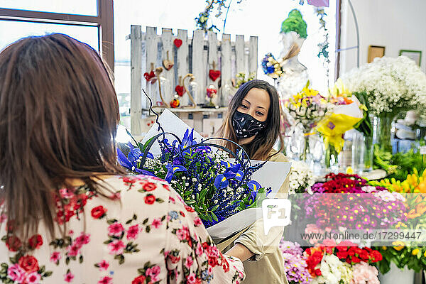 eine unternehmungslustige Frau überreicht ihrem Kunden einen Blumenstrauß
