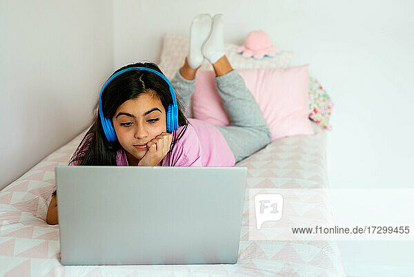 Teenager-Schülerin benutzt Laptop und hört Musik im Bett