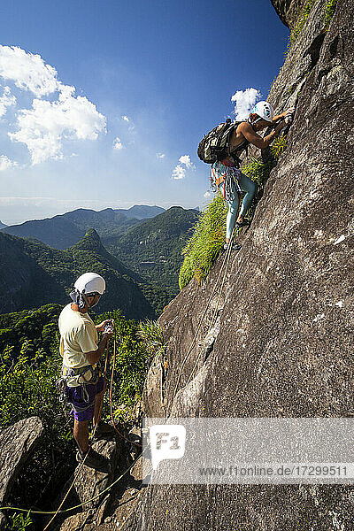 Couple of rock climbers on rocky rainforest mountain in Tijuca Park
