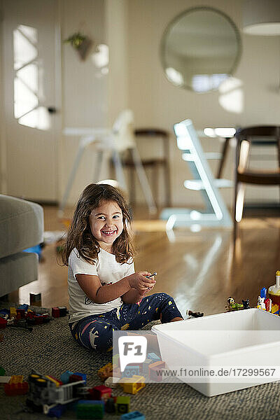Portrait of cute girl smiling while playing with toys at home