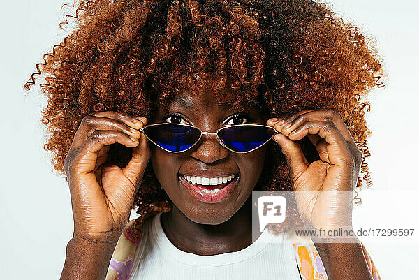 Schwarze junge Frau mit Sonnenbrille schaut in die Kamera