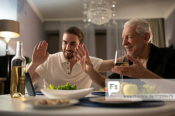 Großvater und Enkel grüßen online Verwandte beim Abendessen