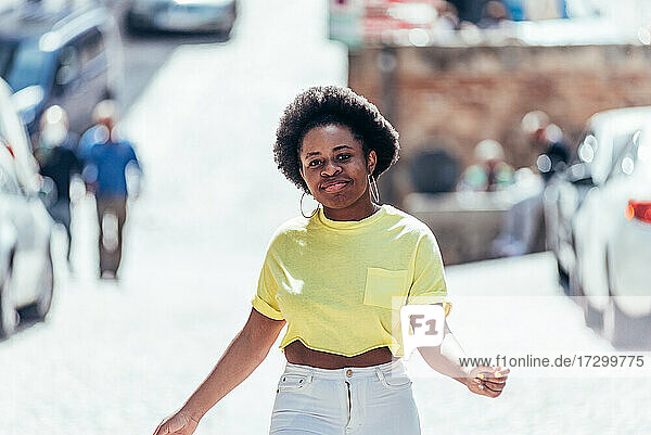 Ein schwarzes Mädchen mit Afro-Haar tanzt auf der Straße in der Stadt.