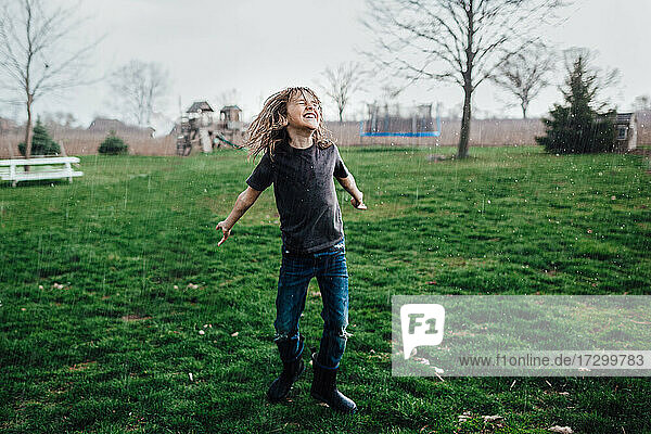 little boy laughing and dancing in the rain