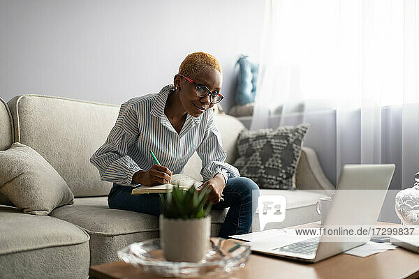 Schwarze Geschäftsfrau arbeitet mit Laptop und Papieren zu Hause