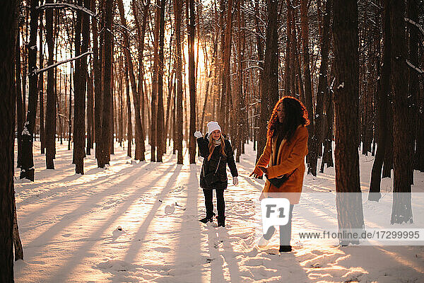 Glückliche Freundinnen spielen mit Schnee im Park im Winter