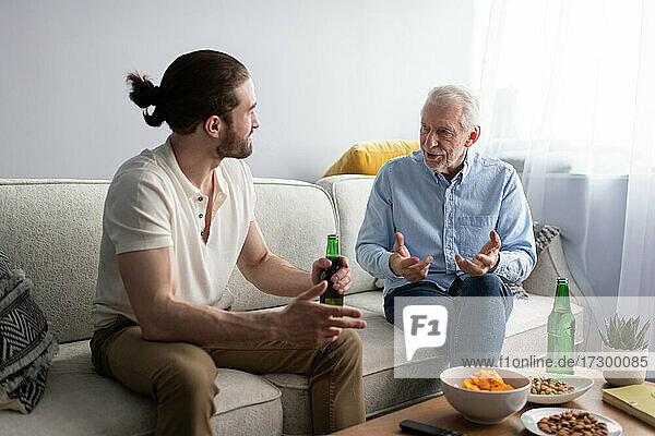Grandson and grandfather talking on sofa