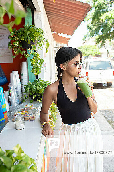 Young woman drinking healthy green juice
