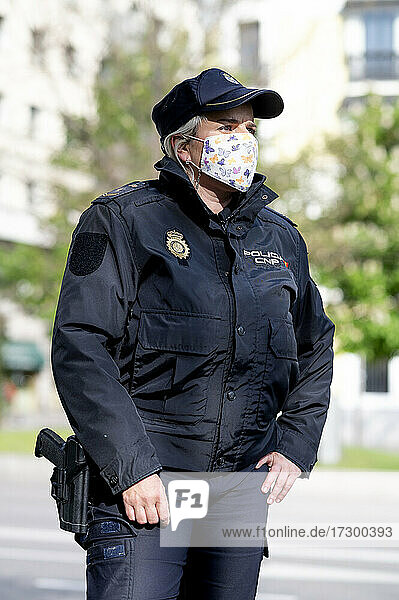 Polizistin  Mitglied der Sicherheitskräfte Spaniens  posiert mit einer Maske - New normal concept