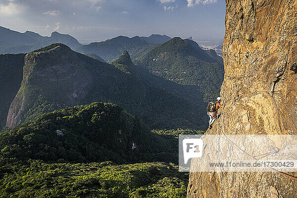 Schöner Blick auf Bergsteigerin auf steilem felsigem Regenwaldberg