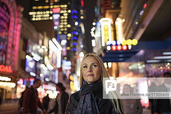 Adult woman on glowing city street in evening