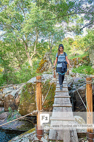 Weiße  kaukasische Frau  die eine Holzbrücke in der Natur überquert
