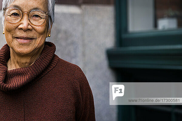 Porträt einer lächelnden älteren Frau mit Brille in der Stadt