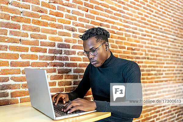 junger afrikanischer Mann  der an seinem Laptop arbeitet