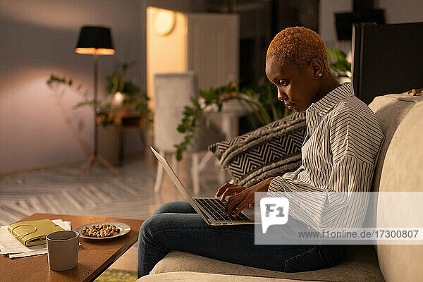 Junge schwarze Frau  die zu Hause an einem freiberuflichen Projekt am Laptop arbeitet