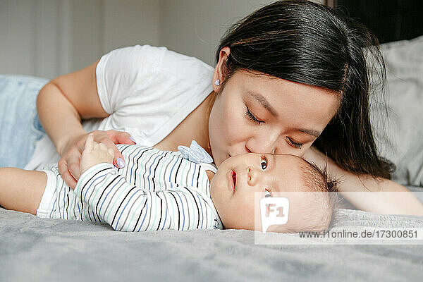 Muttertag Urlaub. Stolze asiatische Mutter umarmt küssend neugeborenen Sohn.