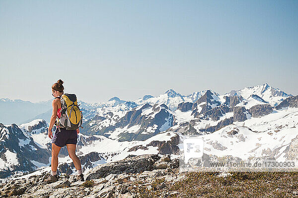 rear view of attractive fit woman backpacking in the mountains.