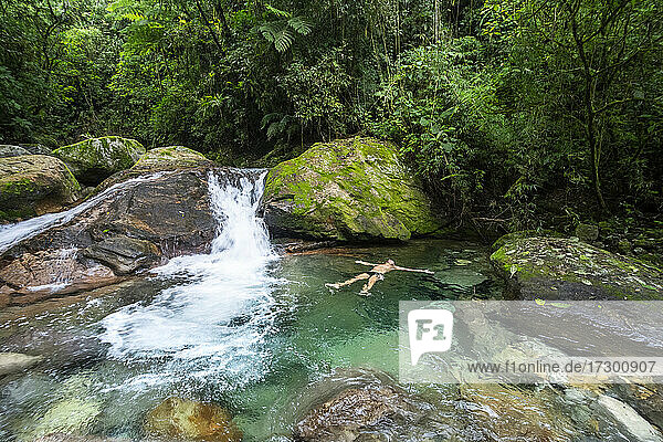 Man enjoying beautiful crystal clear water rainforest waterfall