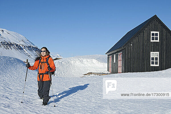 Frau  die von einer Skihütte in Island aus zu einer Wanderung aufbricht