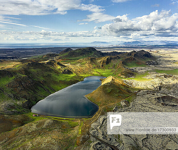Drohnenansicht eines ruhigen Sees in bergigem Gelände an einem bewölkten Tag in Island