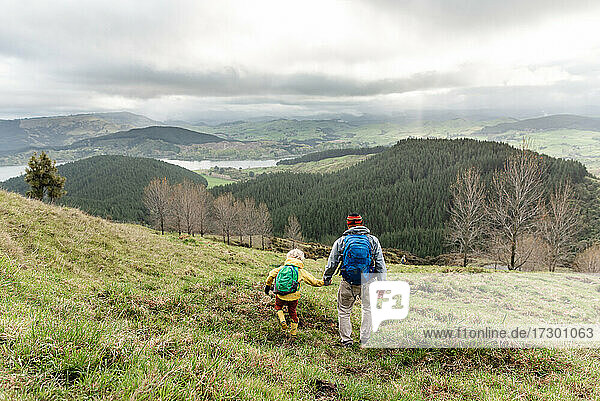 Child and dad walking together in New Zealand hillside