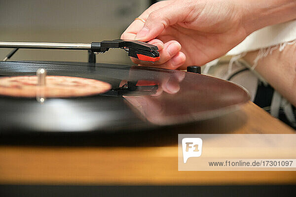 Nahaufnahme einer Hand  die eine Schallplatte auf einem Plattenteller abspielt