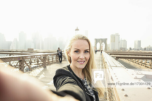 Lächelnde Frau nimmt Selfie auf städtischen Stadt Brücke