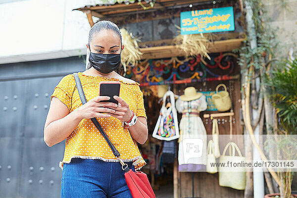 Junge Frau mit Maske vor einem lokalen Handwerksmarkt
