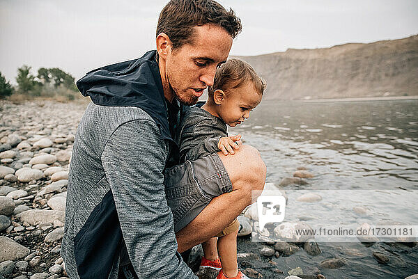 Dad and toddler son explore waters edge of Yellowstone River