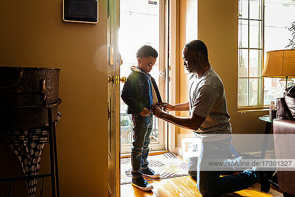 Vater hilft seinem Sohn beim Anziehen am Eingang des Hauses
