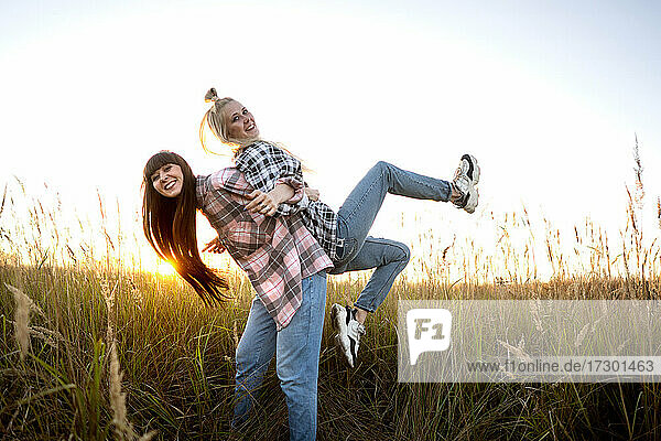 two beautiful twin girls make style in the field at sunset